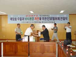 ▲ 전상용 늘푸른 21회장이 박윤서 예당내수면계장에게 미생물탈취제를 전달하고 있다.