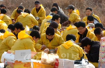 ▲ 3일 태안군 구례포 해녀마을 해안가에서 방제작업을 펼친 우석건설 직원들이 강추위 속에서도 식사를 하며 자원봉사를 펼쳤다.	/특별취재반