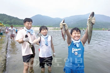 ▲ 솟대마을의 물고기잡기 체험에 참여한 어린이가 양손에 물고기를 잡고 즐거워하고 있다.