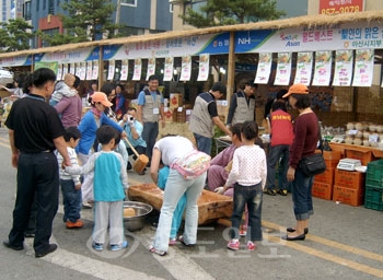 ▲ 백제문화제를 찾은 관광객들이 6일 부여 구드래 공원 농협 직거래 장터에서 떡 메치기 행사를 즐기고 있다.