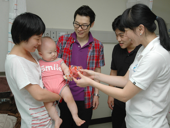 ▲  사진 오른쪽부터 엄마에 안겨있는 아기의 손에 사과를 쥐어주는 전다혜 선수와 이승재 감독, 엄성흠 팀장.