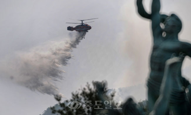 ▲ 휴일인 3일 오전 11시46분께 대전시 유성구 갑동 갑하산에서 화재가 발생,대전 현충원 상징탑 뒤편으로 산림청 산불 진화용 헬기가 산불발생 지역에 진화작업을 벌이고 있다. 김상구 기자 ttiger39@ 