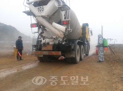 ▲ 60대 후반의 마을주민으로 구성된 방역요원들이 25일 오전 비를 맞으며 차량소독을 하고 있다.