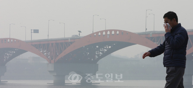 서울시는 24일 낮 기준으로 대기 중 초미세먼지 농도가 '주의보' 수준으로 높아졌다고 밝혔다. 낮 서울 대기의 초미세먼지(PM-2.5) 농도는 92㎍/㎥를 기록했다. 사진은 이날 서울 마포구 한강시민공원 망원지구에서 손수건으로 입과 코를 가린 한 시민이 산책하는 모습. 
<br />연합뉴스