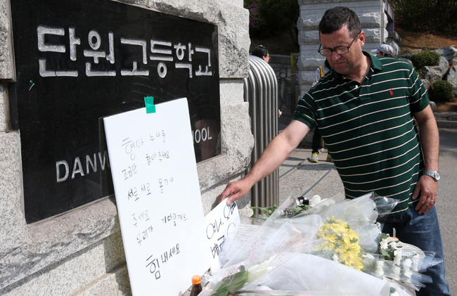 ▲ '세월호' 침몰 닷새째인 20일 오전 안산 단원고등학교를 찾은 한 외국인이 정문에 세워진 '언니 오빠 빨리 와'라는 무사귀환 기원 팻말이 바람에 날려 떨어지자 바로 세우고 있다. 
<br />연합뉴스