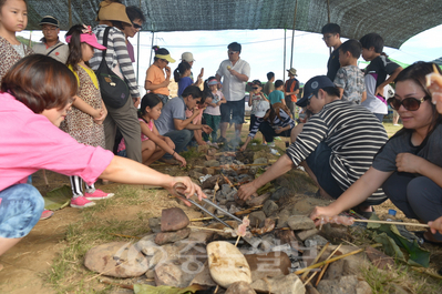 ▲ 석장리 세계 구석기 축제에서 구석기인과 같이 생선, 생고기, 옥수수 등을 꼬치에 끼워 숯불에 구워먹는 체험을 하고 있다.