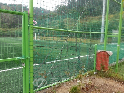 축구장으로 진입하는 철문이 자물쇠로 굳게 잠겨 있지만 바로 옆에 성인 한명이 들어갈 수 있도록 그물이 찢어져 있다.