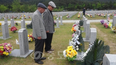 ▲ 현충일을 하루 앞둔 5일 함께 군생활한 고인을 만나러 온 최현식(사진 왼쪽)씨가 묘비 앞에서 묵념하고 있다.