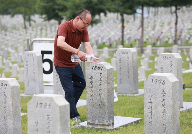 ▲ '곧 시원한 비가 올거에요' 
<br /> 6·25 전쟁 65주년을 하루 앞둔 24일 오후 서울 동작구 서울현충원을 찾은 신상철씨가 1950년 7월 문경지구에서 전사한 작은아버지 고(故)신현홍 중령의 묘비에 물을 뿌려주고 있다./연합