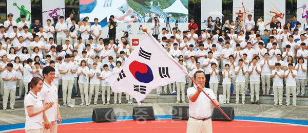 ▲ 25일 오후 서울 송파구 방이동 올림픽공원 수변 무대에서 '사랑을 주세요! 자랑으로 드리겠습니다'라는 슬로건으로 열린 2015 광주 하계유니버시아드 대회 대한민국 선수단 결단식에서 선수단장인 유병진 명지대 총장이 단기(태극기)를 김정행 대한체육회장으로부터 받아 흔들고 있다./연합뉴스 제공