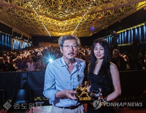 ▲ 김민희와 홍상수 감독의 불륜설이 팬들을 충격에 빠트렸다. 사진은  홍상수 감독이 지난 2015년 스위스 로카르노에서 열린 시상식에서 배우 김민희와 함께 기념 촬영을 하고 있는 모습./연합뉴스