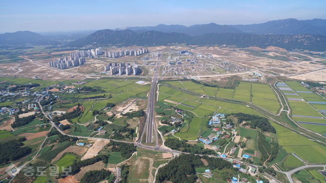 ▲ 논과 밭, 축사가 있는 초록빛의 홍성군 홍북면(예산군 삽교읍) 농촌 마을과 이를 일부 개발해 아파트 숲이 돼버린 흙빛의 내포신도시, 멀리 용봉산이 한 눈에 보인다.
<br />원주민들은 용봉산 조망권 실종과 신도시 냉난방을 위한 집단에너지 연료로 인한 환경오염 우려, 축사 냄새로 인한 눈치 등을 한 몸에 받고 있다. 내포신도시 출범 5년이 지난 시점, 이제는 원주민들이 변화 요구를 감내하는 처지다./충남도 제공.