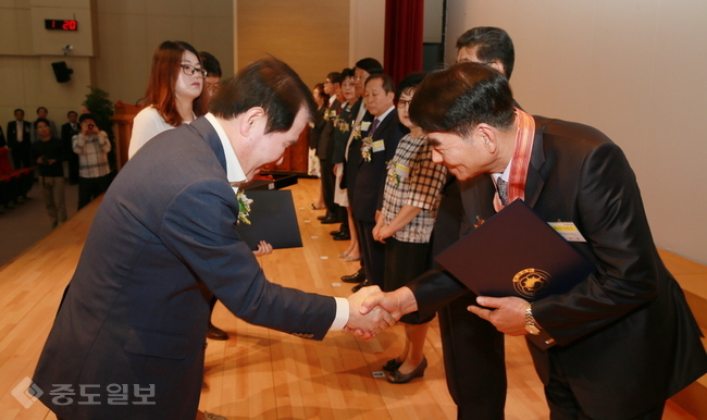 ▲ 김지철 도교육감(왼쪽)이 퇴임 교원에게 훈장을 전달하며 인사하고 있다./충남교육청 제공.