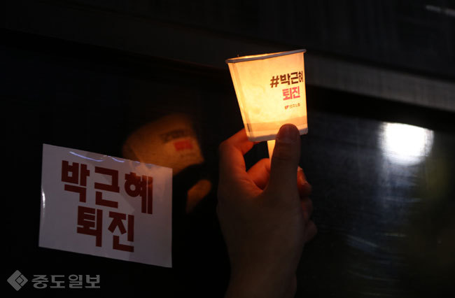 ▲ 12일 광화문에서 열린 박근혜 대통령 퇴진 3차 집회에서 한 시민이 촛불을 들고 있다./연합