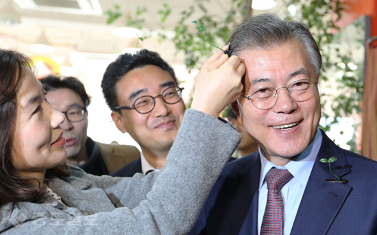 ▲ 더불어민주당 문재인 전 대표가 7일 대전 서구 한 카페에서 열린 중증장애아 보호자 간담회에서 어린이 재활병원 건립을 위한 '기적의 새싹 핀'을 머리에 달고 있다. 연합 ▲ 더불어민주당 문재인 전 대표가 7일 대전 서구 한 카페에서 열린 중증장애아 보호자 간담회에서 어린이 재활병원 건립을 위한 '기적의 새싹 핀'을 머리에 달고 있다. 연합