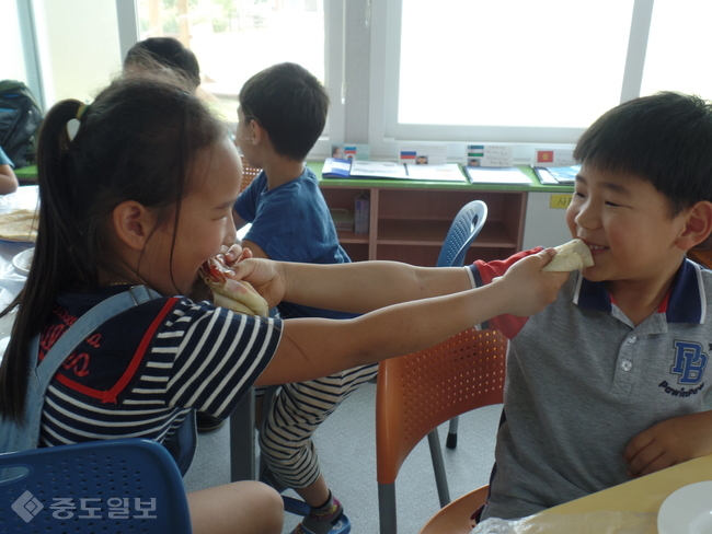 ▲ 당진 합도초등학교 학생들이 직접 만든 러시아식 팬케이크 '블리니'를 서로 먹여주고 있다./충남도교육청 제공.