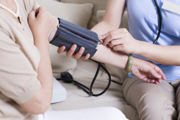 Nursing assistant taking senior woman's blood pressure