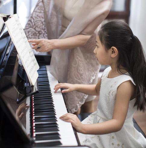 Grandmother teaching granddaughter to play the piano