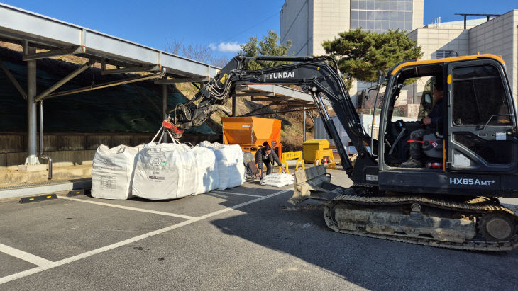 굴착기가 겨울철 제설 작업에 사용할 염화칼슘을 옮기고 있다.(