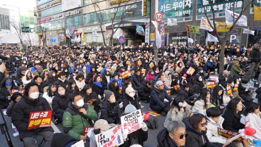 14일 오후 `윤석열 탄핵 대전시민대회`에 참석한 시민들이 윤석열 대통령 탄핵 표결 결과를 기다리고 있다.(영상캡처사진) 금상진 ``총 투표수 300표 중 가 204표`` 윤석열 대통령의 탄핵소추안이 가결되는 순간, 대형 모니터를 숨죽이며 지켜보던 시민들은 일제히 환호성을 지르며 윤석열 대통령의 탄핵을 환영했다. 14일 오후 대전시 서구 둔산동 은하수네거리에서 열린 `윤석열 탄핵 대전시민대회`에는 집회 시간이 시작되는 3시 이전부터 수천 명의 시민이 운집하며 도로 위를 채우기 시작했다. 이날 경찰은 대덕대로 은하수네거리부터 방죽네거리까지 4개 차로 중 3개 차선을 통제해 참가자들이 안전하게 집회에 참석할 수 있도록 배려했다.체감온도 영하의 추운 날씨에도 불구하고 집회 현장에는 6000여 명(경찰추산)의 시민들이 운집해 국회의 탄핵소추안 표결을 기다렸다. 표결 시작에 앞서 윤석열 퇴진을 주제로 한 서예 퍼포먼스를 비롯해 비상계엄부터 탄핵 표결까지 촛불과 응원봉으로 겨울밤을 밝혔던 시민들의..